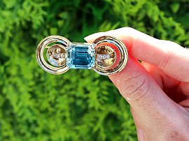 holding aquamarine diamond brooch